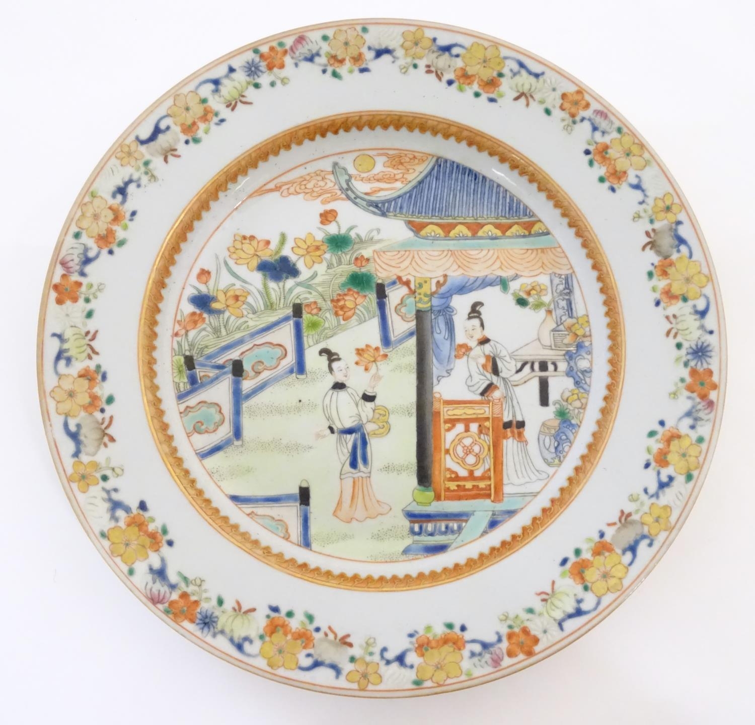 A Chinese plate depicting two ladies in a garden terrace with flowers, foliate, vases, etc.