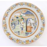 A Chinese plate depicting two ladies in a garden terrace with flowers, foliate, vases, etc.