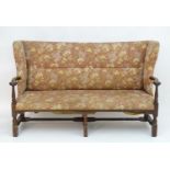 A mid 18thC wingback sofa with scrolled arms and an upholstered backrest and seat above a