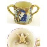 A majolica loving cup / twin handled mug decorated with moulded figures in relief amongst vine