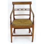 A Regency elm East Anglian armchair with a shaped top rail, reeded frame and drop in seat above