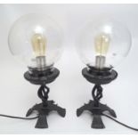 A pair of late 20thC table lamps, the cast bases supporting spherical clear glass shades, each 18"