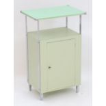 An Art Deco bathroom / bedside cabinet, the mint green glass top supported by chromed mounts above a