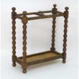 An early 20thC carved oak umbrella / stick stand with four bobbin turned supports mounted by