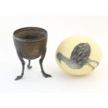 An ostrich egg with hand painted bird detail. Together with a cast metal stand supported by three