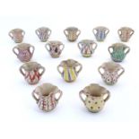 Fourteen Continental faience style twin handled cups of quatrefoil form with hand painted
