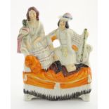 A Staffordshire flatback figural group of a man with a musical instrument and a woman with a parrot,
