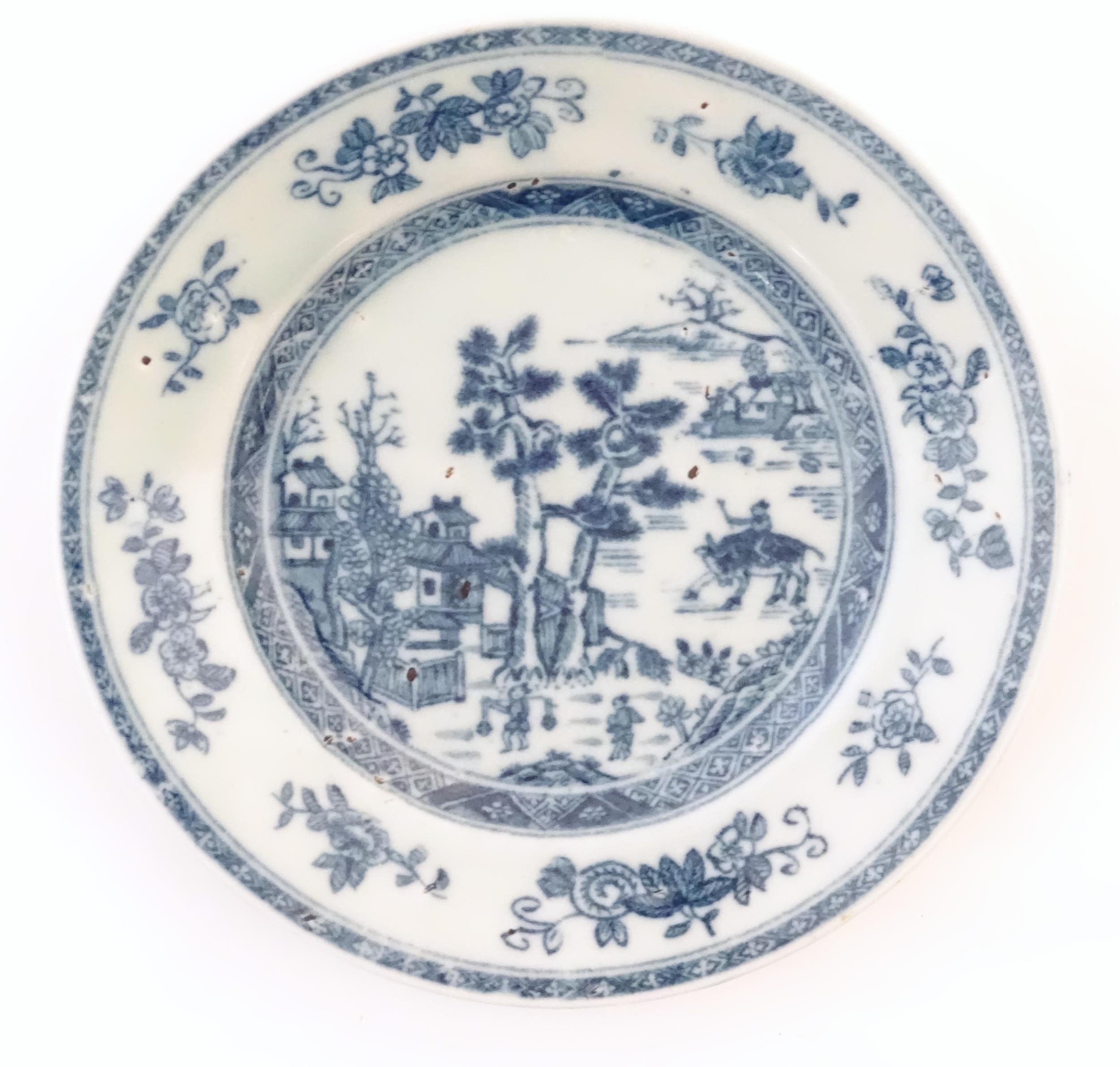 A Chinese blue and white plate depicting a landscape scene with figures, trees, pagodas etc. with
