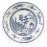 A Chinese blue and white plate depicting a landscape scene with figures, trees, pagodas etc. with