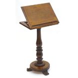 A mid 19thC mahogany reading / music stand with an adjustable slope above a turned pedestal and