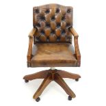 A late 20thC desk chair with deep buttoned leather upholstery and shaped arms above a five spoke