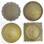 Four assorted Eastern brass trays / table tops, each with incised decoration, the largest 25" in