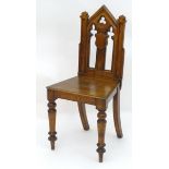 A mid 19thC oak Gothic hall chair with a pointed back, trefoil decoration and pierced lancet