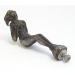 A 20thC cast bronze car mascot formed as a nude woman with bent knees and arms, in the manner of