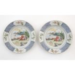 A pair of Chinese plates depicting a two figures in a garden watching a bat, with sea and