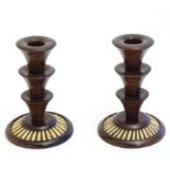 A pair of 20thC treen candlesticks with stepped columns and porcupine quill detail to base.