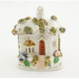 A Staffordshire pottery pastille burner modelled as a cottage, decorated with encrusted flowers.