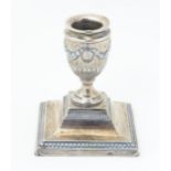 A silver candlestick of urn form on a squared base, hallmarked London 1904, maker Samuel Smith & Son