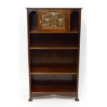 An early 20thC mahogany Glasgow School style bookcase with a rectangular top above a floral embossed
