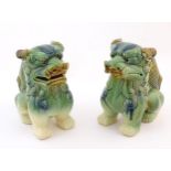 A matched pair of Chinese models of foo dogs / guardian lions with a green, blue and ochre glaze.