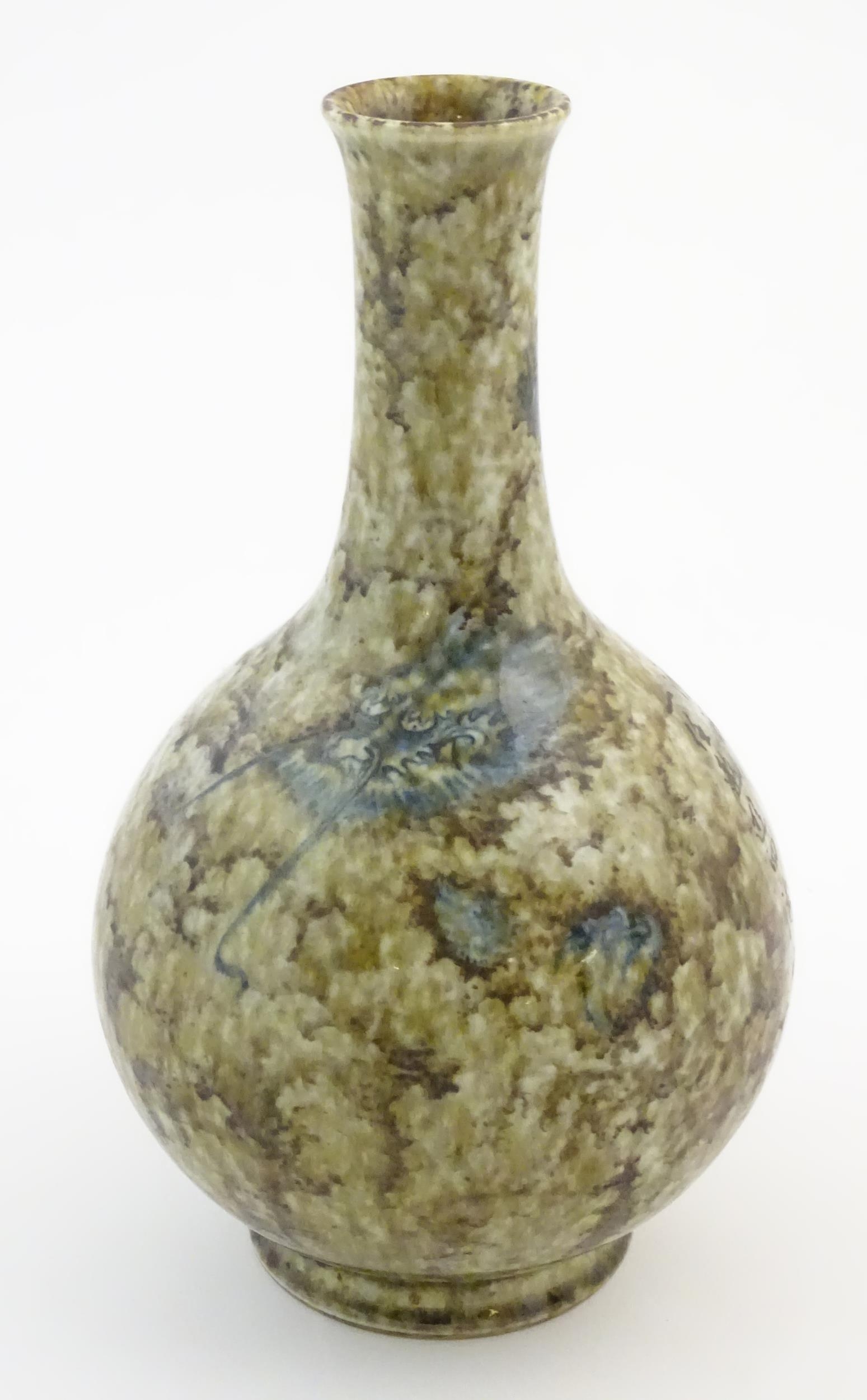 A Chinese bottle vase with a mottled glaze decorated with a stylised dragon face and claws, and