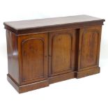 A 19thC mahogany sideboard with a rectangular top above three moulded panelled doors, having three