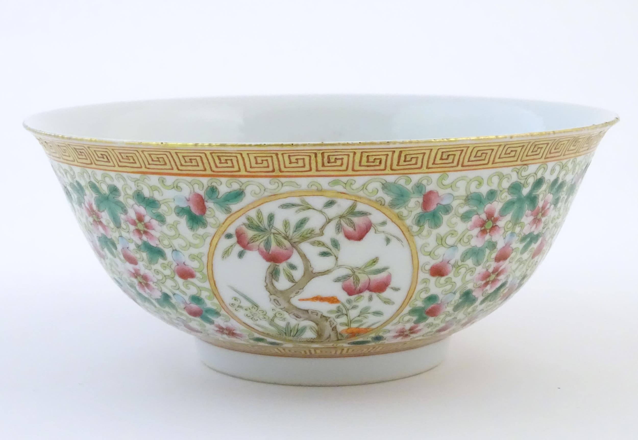 A Chinese famille verte bowl decorated with fruiting trees and landscapes scenes in roundels and