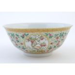 A Chinese famille verte bowl decorated with fruiting trees and landscapes scenes in roundels and