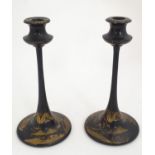 A pair of late 19thC lacquered candlesticks with chinoiserie decoration depicting a woman and a