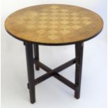 A 20thC games table with a circular top having a playing surface and surrounded by anthemion and