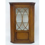 A Victorian hanging oak corner cupboard with a moulded cornice above an astragal glazed door an