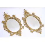 A pair of late 19thC / early 20thC gilt mirrors with gilt and gesso frames and oval mirrored glass