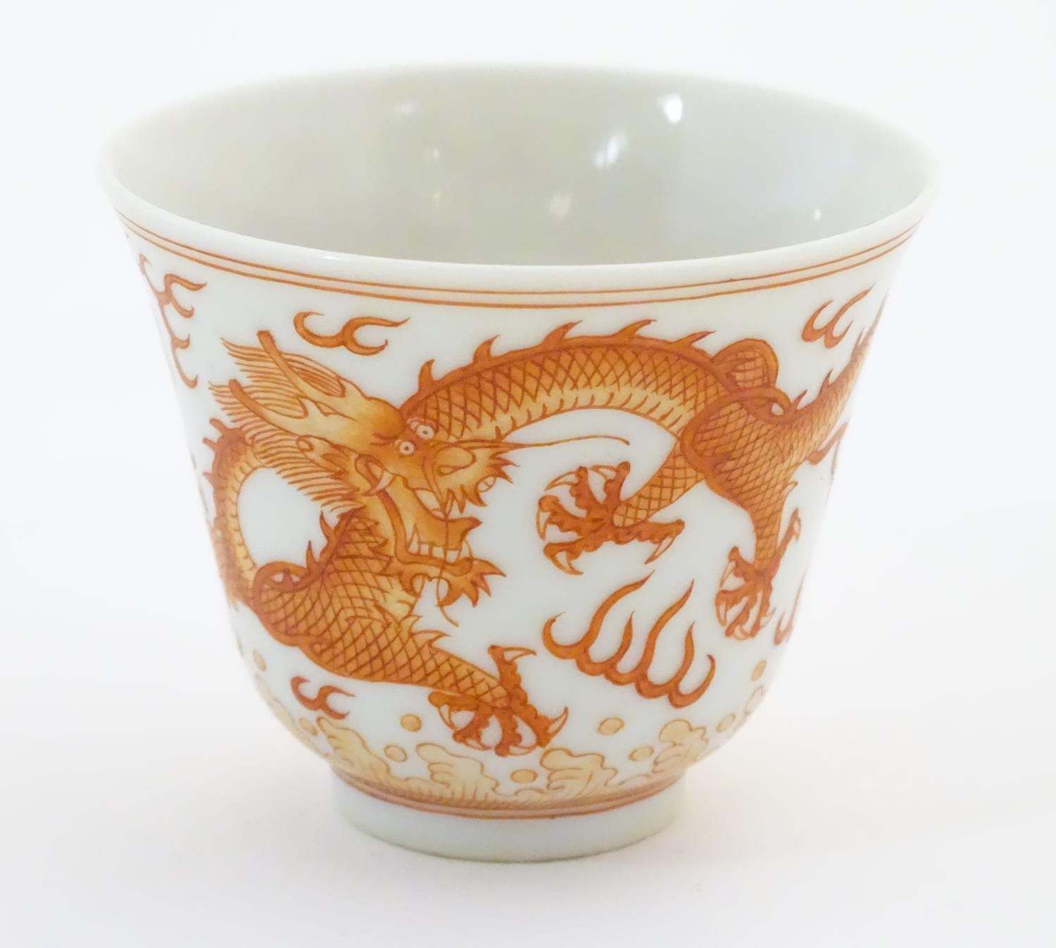 A Chinese wine cup with dragon detail and stylised flaming pearls and clouds. Character marks under.