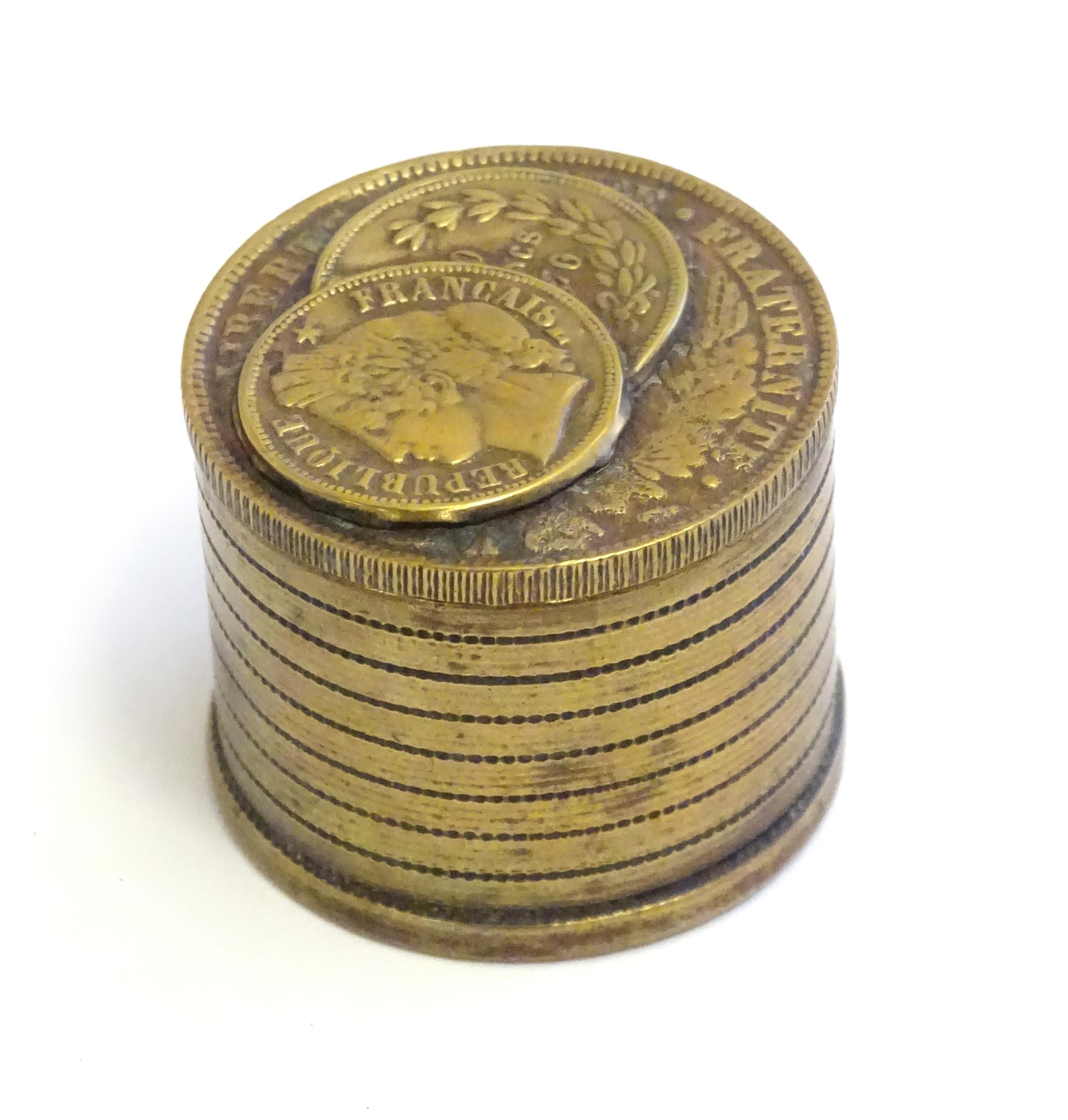 A 20thC Continental cast inkwell modelled as stacked coins, with applied French coins to top.