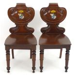A pair of 19thC mahogany hall chairs shaped, carved backrests and later armorials to the centre,