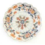 An Oriental plate with a scalloped rim decorated in the Imari palette with floral and foliate