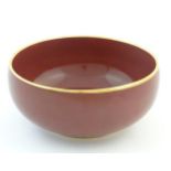 A Japanese bowl with a red glaze and gilt rim. Character marks under. Approx. 4" high x 8 1/2"