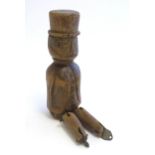 A 19thC folk art carved wooden naive model of a gentleman wearing a top hat, with articulated