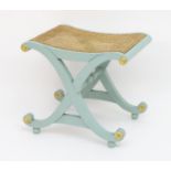 A Regency style painted X frame stool with gilt highlighted roundels and a caned seat. 20" wide x