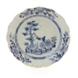 A Chinese blue and white plate with a lobed rim decorated with a landscape scene with trees and
