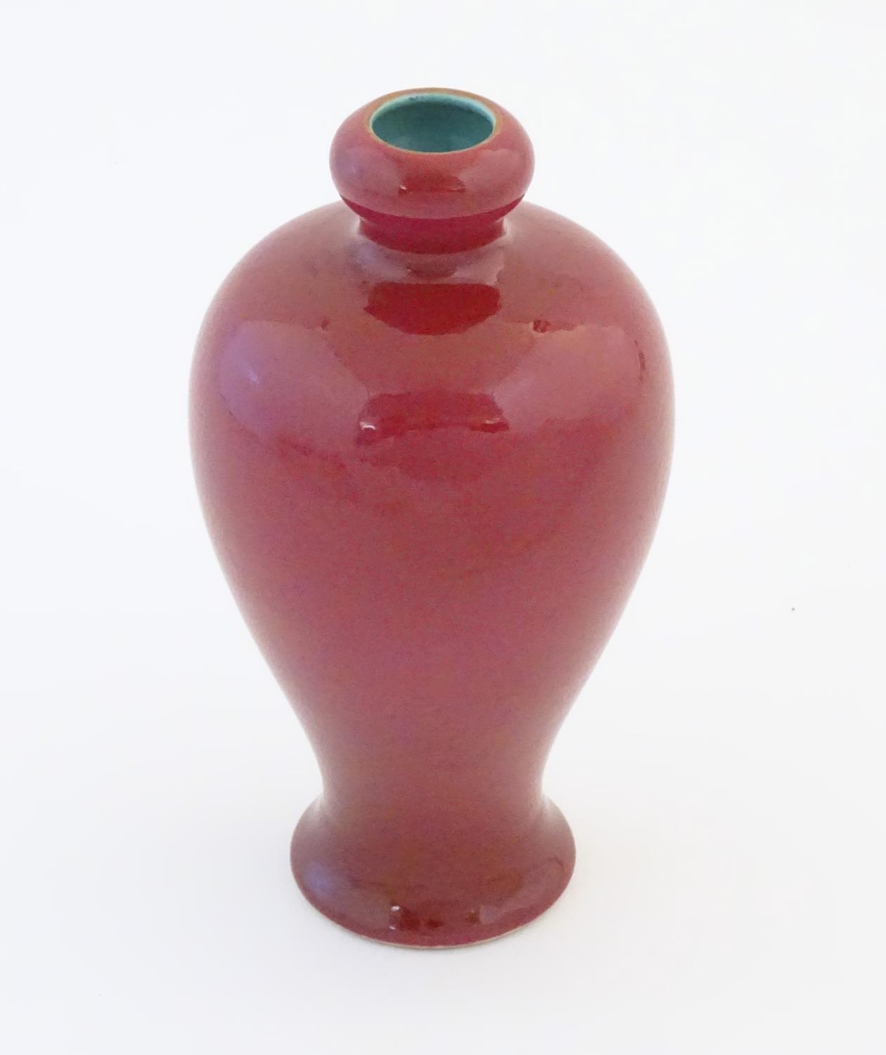 A Chinese baluster vase with a bulbous rim, with a ruby pink glaze and a turquoise interior.