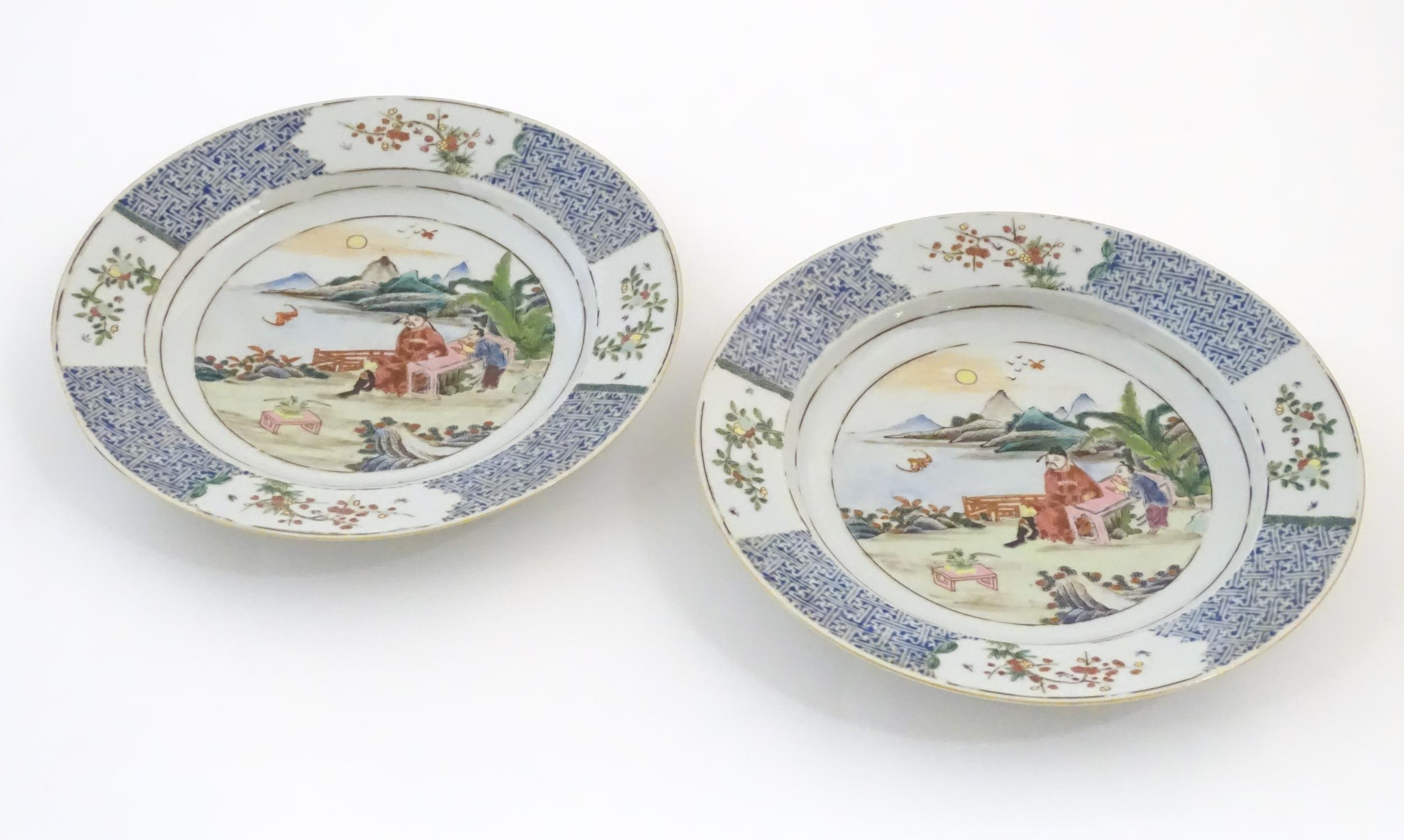 A pair of Chinese plates depicting a two figures in a garden watching a bat, with sea and - Image 3 of 5