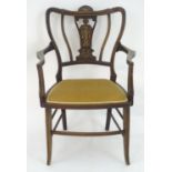 An Edwardian marquetry inlaid chair, with a shaped backrest, swept arms and standing on tapering