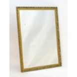 A mirror with a gilt moulded frame having beadwork decoration and floral detailing surrounding a