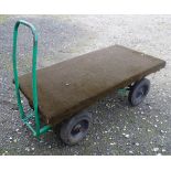 A grocer's barrow / trolley, the steel frame with four wheels, steering handle and solid platform.