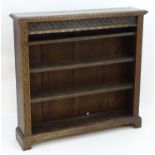 An early 20thC oak bookcase with a carved cornice above a carved frieze and four shelves flanked