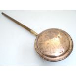 A 19thC copper bed warming pan with a turned beech handle, the lid decorated with folk art depiction