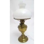 An early 20thC brass oil lamp, converted to electricity, the lobed body supporting a milk glass