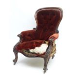 A Victorian mahogany button back armchair with a moulded frame and floral carved arms and legs.