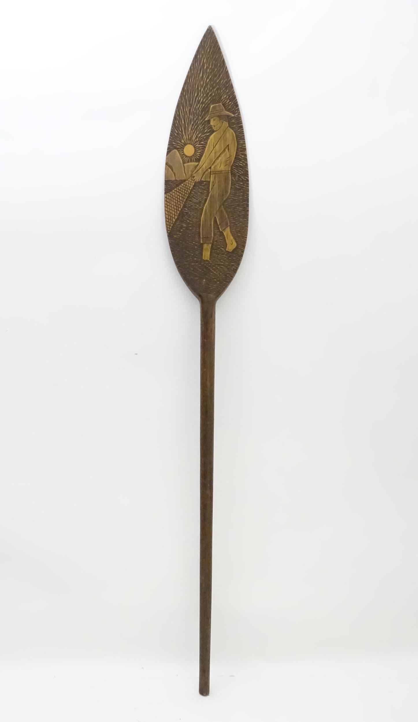 A Brazilian boat oar / paddle with carved decoration a man fishing with a net. Ascribed 'Itatiaia,